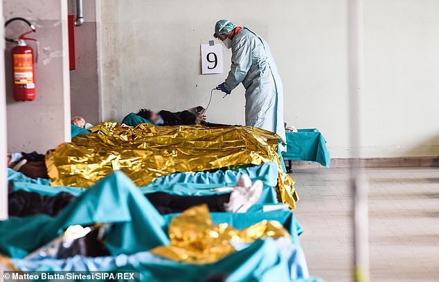 A medic wearing a protective suit and face mask works at a triage centre in Brescia, in the region of Lombardy which has been worst affected by the crisis